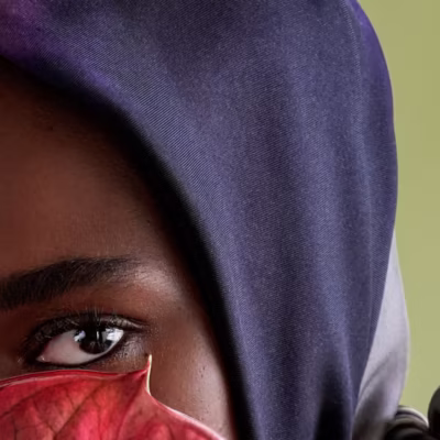 Primo piano di una modella di colore, con un foulard in testa, sulle tinte del blu notte
