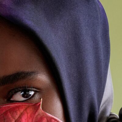 Primo piano di una modella di colore, con un foulard in testa, sulle tinte del blu notte